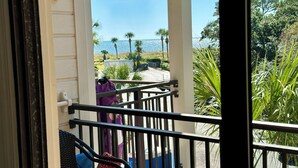 En balkon med udsigt over havet og palmer.