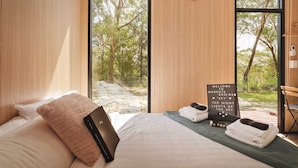 Un dormitorio moderno con una cama, una computadora portátil, un cartel de bienvenida y vistas a árboles.