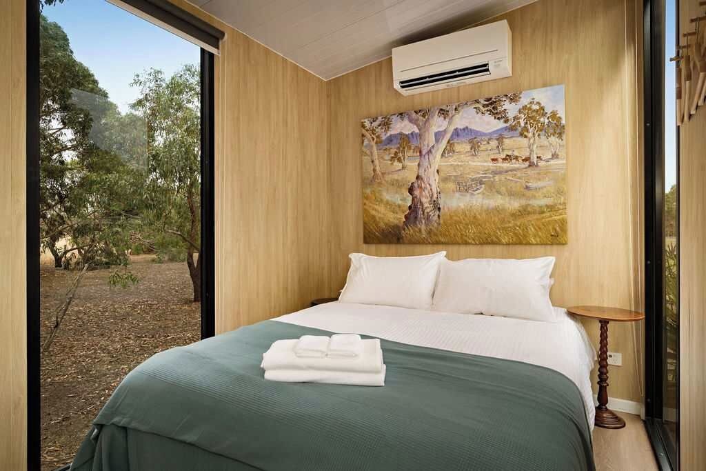 Ett hotellrum med en stor säng, en tavla som föreställer ett landskap och en luftkonditioneringsanläggning på väggen.