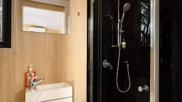Ein modernes Badezimmer mit einer begehbaren Glasdusche, einem weißen Waschbecken und einem Holz-Waschtisch.