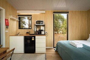 A compact room with a kitchenette, a bed, and a view of trees. - Bush Serenity by the Sea by Tiny Away (Bolwarra)