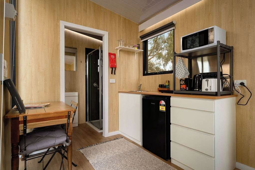 Une cuisine compacte dotée d’un plan de travail en bois, d’un four à micro-ondes, d’une machine à café et d’un réfrigérateur.