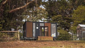 A modern, compact cabin with a wooden exterior, large windows, and a small porch area. - Dreamy 1 by Tiny Away (Red Hill)