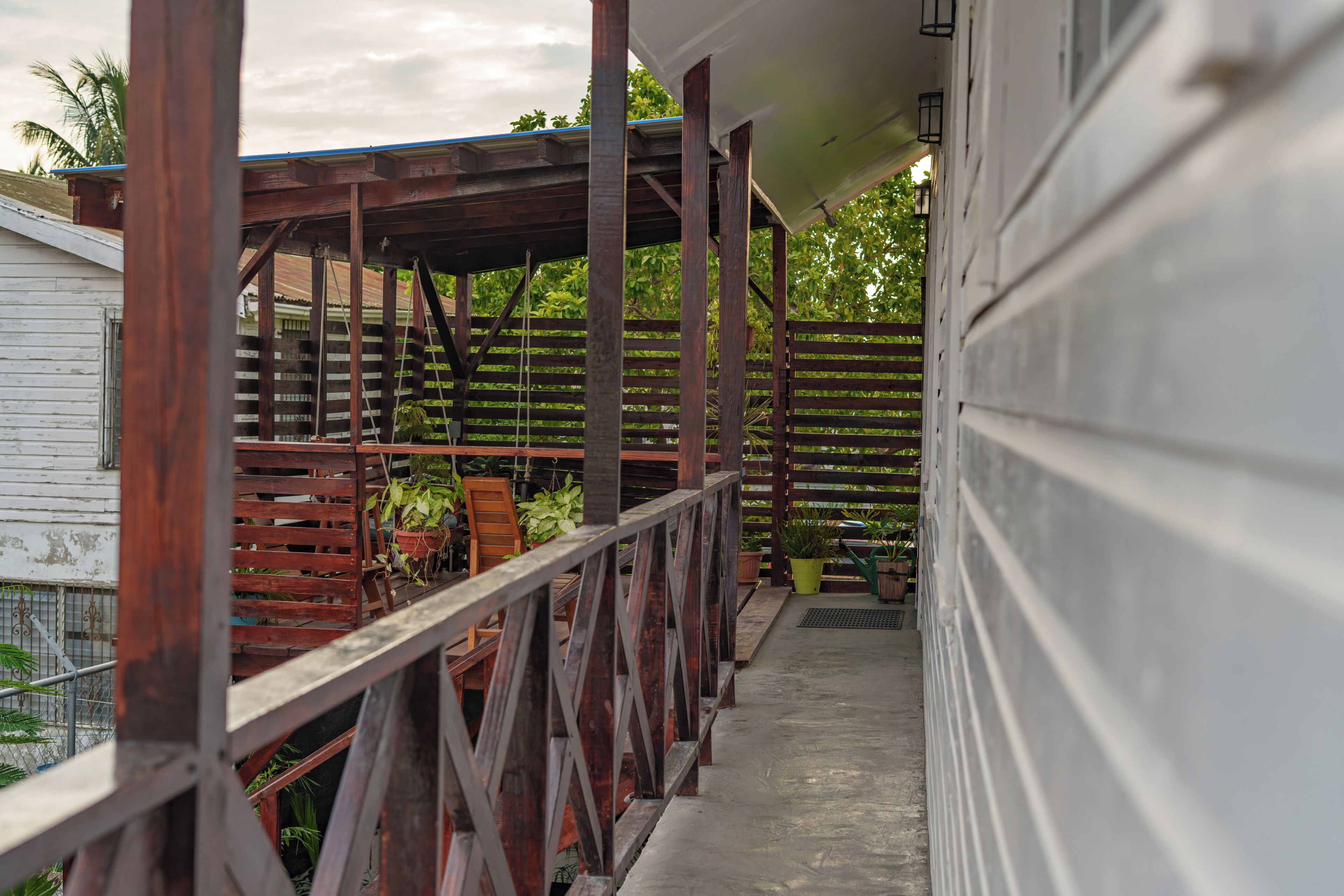 A covered porch with wooden railings and potted plants.