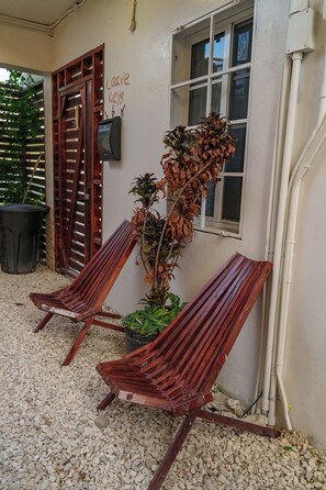 Two wooden lounge chairs outside a building with a window and a sign that says "Leave Keys". - Casa De Shangrila Boutique Hotel (Belize City)