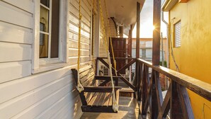 Eine hölzerne Veranda mit einer Bank, einer Treppe und einer gelben Wand.