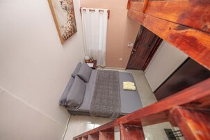 Un dormitorio con una cama, una mesita de noche, una lámpara y una ventana con cortina.