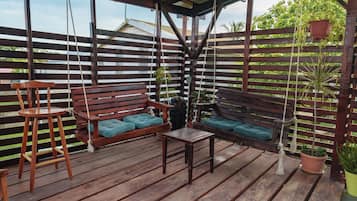 Una terraza de madera con un banco y una mesita.
