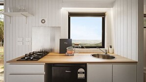 Una cocina compacta con encimera de madera, cocina a gas, lavamanos y ventana con vistas.