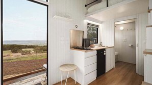 Una cocina compacta con vistas al exterior, un taburete pequeño y una estufa empotrada.