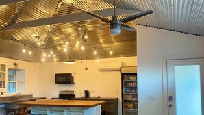 Une cuisine moderne dotée d’un îlot central, de tabourets de bar, d’un ventilateur de plafond et d’un éclairage encastré.