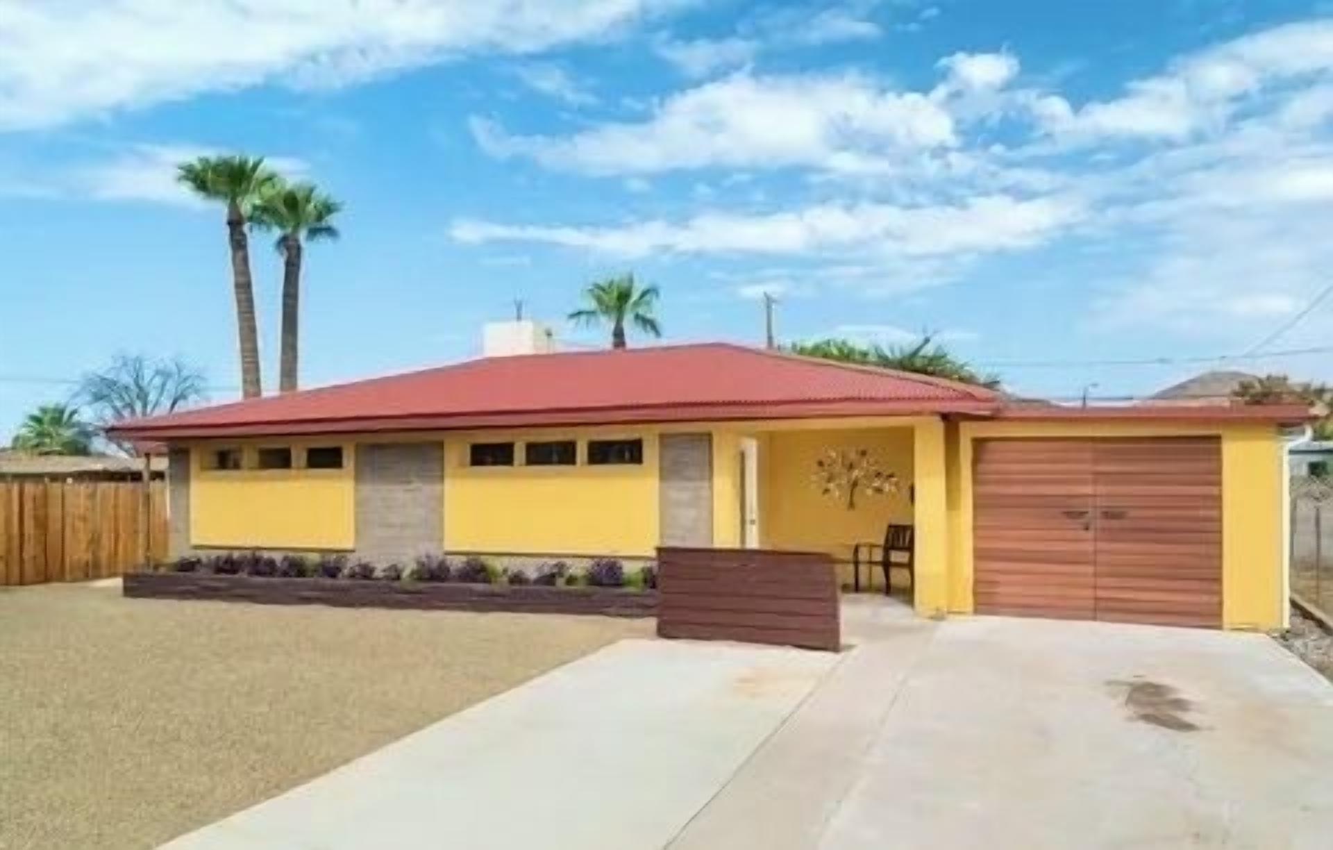 A single-story house with a red roof, yellow walls, and a garage.