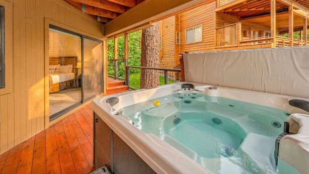 Ein Whirlpool auf einer Holzterrasse mit einer Glastür zu einem Raum.