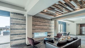 Un hall d’entrée moderne avec un mur orné de motifs, un canapé en cuir et une table basse ronde.