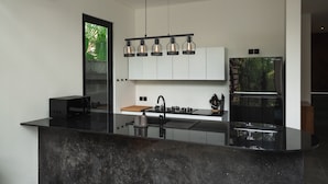Een moderne keuken met een zwart aanrecht, witte kastjes en een zwarte koelkast.