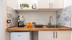 A kitchen with a coffee machine, a fruit bowl, a kettle, and a sink.