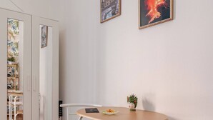 A room with a round table, two chairs, a small potted plant, and two framed pictures on the wall.