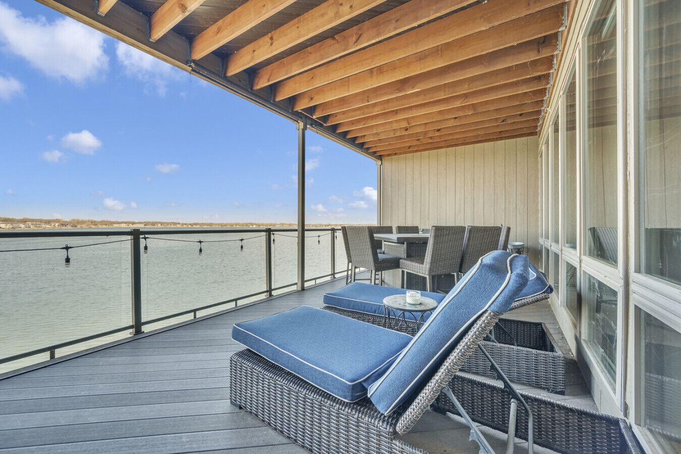 A covered outdoor deck with wicker furniture and a view of the water.
