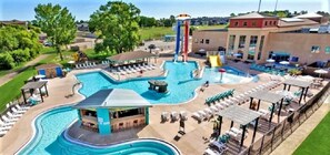 Relax by the resort's large pool, featuring a central water slide and lounge areas.