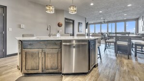 A modern kitchen with a large island, stainless steel appliances, and pendant lighting.