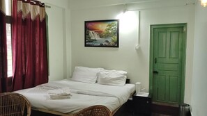 Ein Zimmer mit einem Bett, einem Sessel, einer grünen Tür und einem Bild an der Wand.
