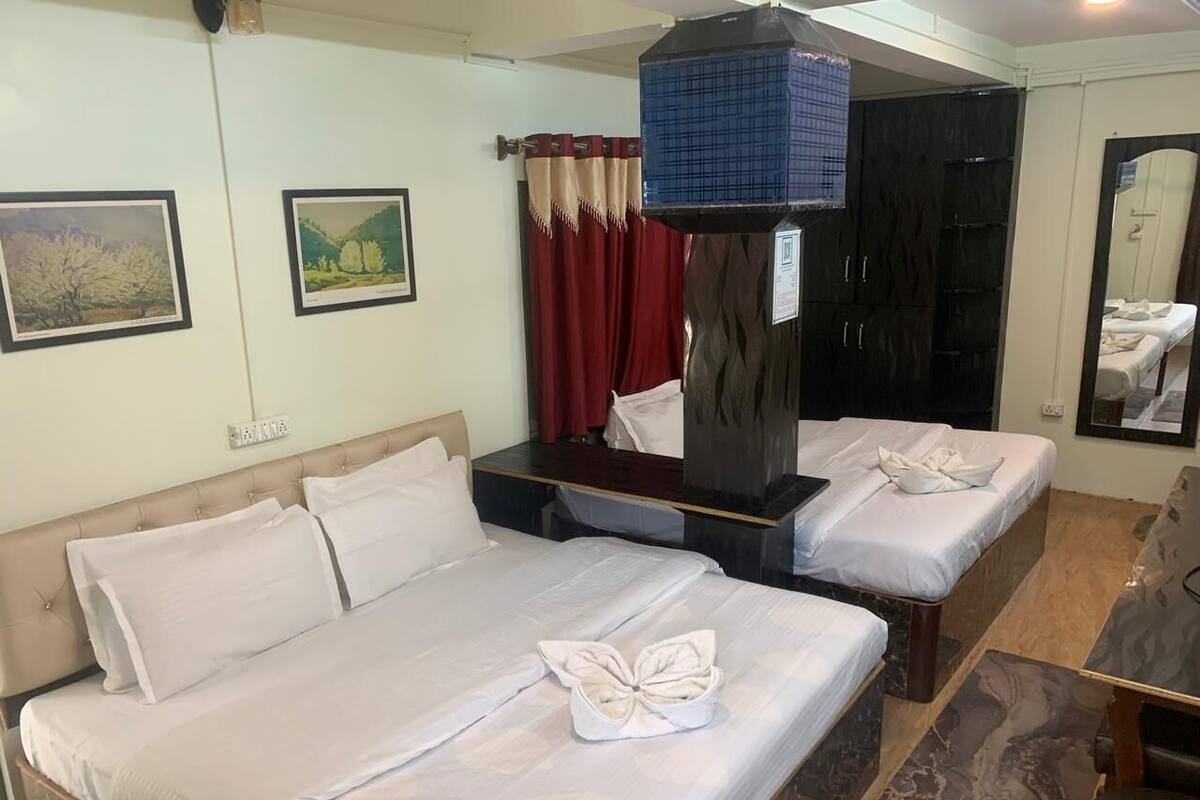 Een hotelkamer met twee bedden, een kast, een spiegel en kunst aan de wanden.