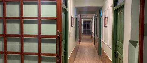 Un couloir doté de portes en bois et de panneaux en verre dépoli, qui mène à plusieurs pièces.
