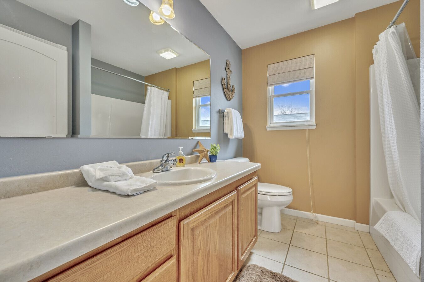 A bathroom with a vanity, sink, and toilet. There is a window with a view of the outdoors.
