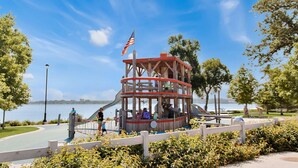 A wooden observation tower with a red roof and an American flag, surrounded by greenery and a lake view.