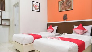 A hotel room with two beds, each with white bedding and red accents, a wooden headboard, a framed artwork on the wall, and a bedside lamp. - Hotel O near Jogja Expo Center formerly Hotel Desa Puri (Baturetno)