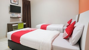 A hotel room with two beds, a desk, a chair, a TV, and a curtain. - Hotel O near Jogja Expo Center formerly Hotel Desa Puri (Baturetno)