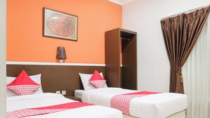 A hotel room with two beds, a nightstand, a lamp, a wardrobe, and a framed picture on the wall. - Hotel O near Jogja Expo Center formerly Hotel Desa Puri (Baturetno)