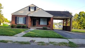 Stroll up to the charming front entrance of this single-story home, featuring a covered porch and a small front yard with a pathway.