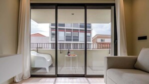 A balcony with a white chair, a small table, and a sofa.