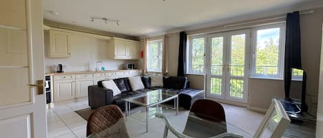 Una sala moderna con una mesa de centro de vidrio, un sofá de cuero y un televisor.
