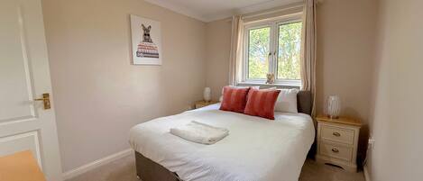 A bedroom with a bed, bedside tables, a window, and a door.