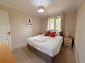 A bedroom with a bed, bedside tables, a window, and a door.