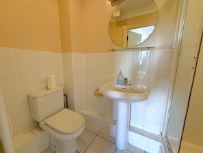 A bathroom with a toilet, sink, and mirror.