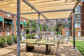 Relax in the shaded patio area, surrounded by lush greenery and comfortable seating.