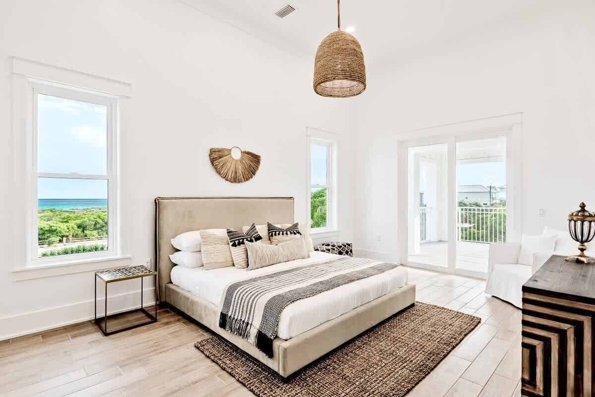 A bedroom with a large bed, a view of the ocean, and a balcony.