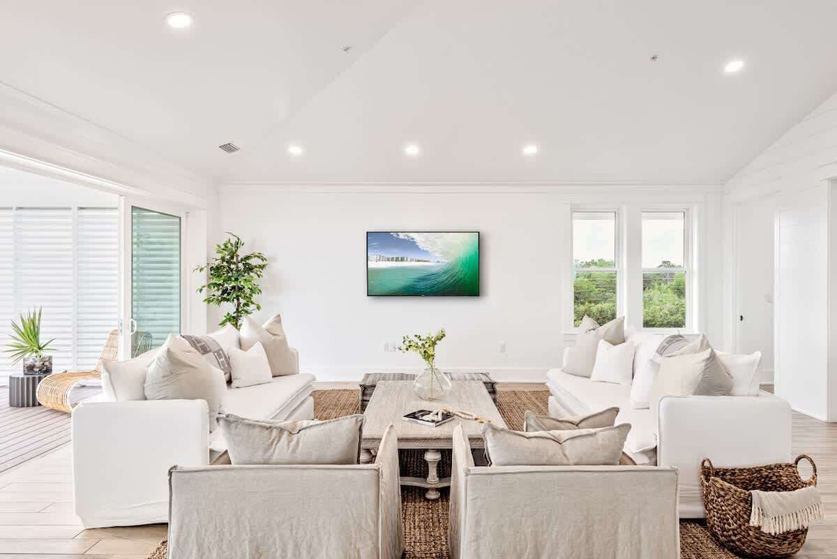 A modern living room with a large window, a painting, and a white sofa set.