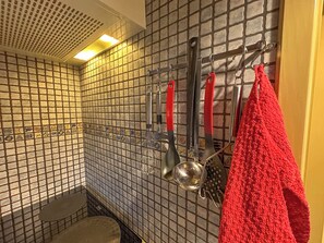 Bathroom features a geometric-patterned backsplash and a toilet, with a towel and kitchen utensils nearby.