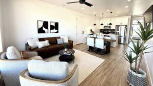 Una sala de estar moderna con un sofá, sillones, una mesa de centro y una obra de arte en la pared.