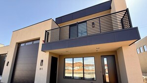 Un edificio moderno de dos pisos con garaje, ventanas amplias y un balcón.