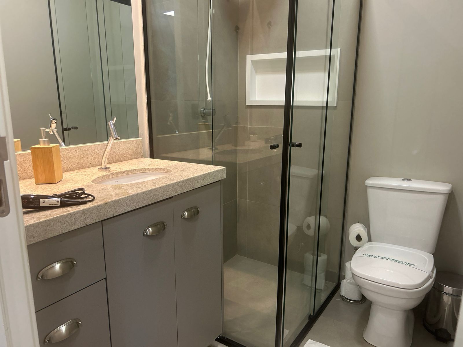Een moderne badkamer met een douchecabine van glas, een toilet en een wastafel met aanrechtblad.