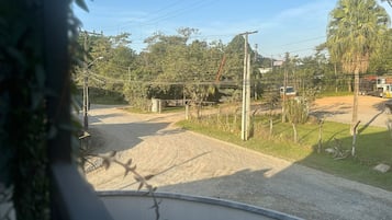 Une route de campagne bordée d’un chemin de terre, de poteaux électriques et d’une végétation clairsemée.