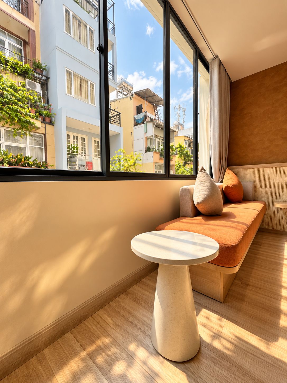 A modern living room with a large window, a round table, and a sofa with cushions.