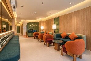 A modern hotel lobby with a reception desk, seating area, and a KOVA sign. - KOVA Hotel - Bui Vien Central (Ho Chi Minh City)