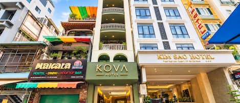 A hotel with a green facade, a rooftop bar, and a sign for Kim Sao Hotel.