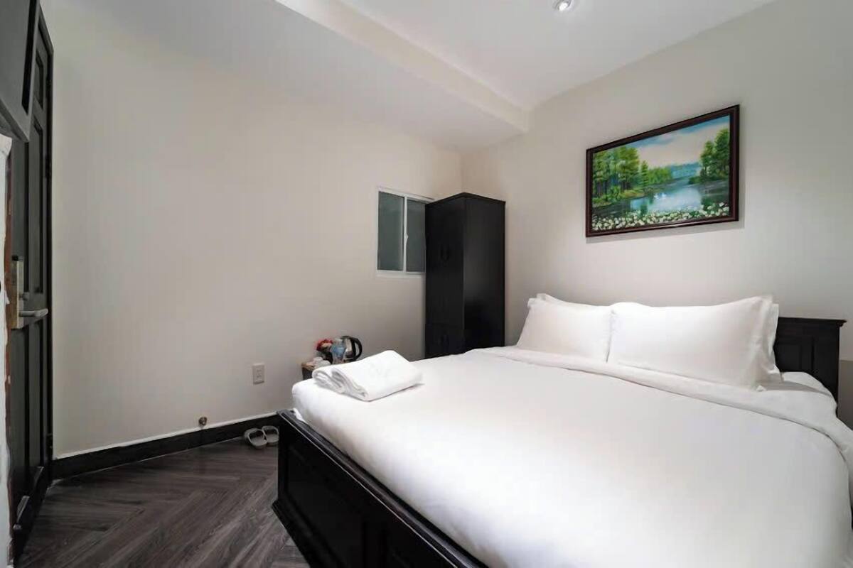Une chambre d’hôtel avec un grand lit, une armoire, un tableau au mur et une petite table avec une lampe.